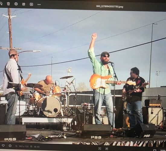 Heath Ledet raising his hand while performing guitar with a band.