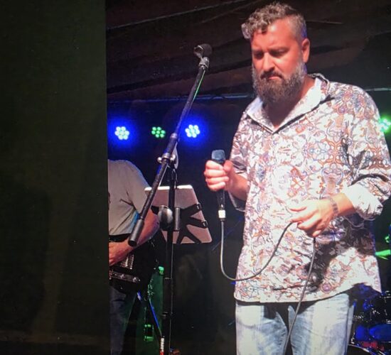 Heath Ledet singing into a microphone during a live stage performance.